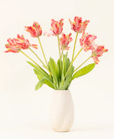 Eine Vase mit weißer Struktur zeigt den Seiden-Kunstblumenstrauß French Parakeet Tulip rot/gelb mit naturgetreuen roten und gelben Tulpen mit grünen Blättern vor einem schlichten hellen Hintergrund.