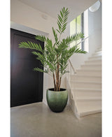De Kunstplant Hawaii Parlour 180 cm, een hoge indoor kunstpalm met weelderige groene bladeren, staat op een grijze vloer in een moderne hal in de buurt van een witte trap en zwarte deur.
