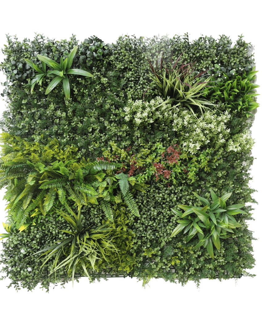Die künstliche Hecke Prestige 100 x 100 cm UV ist eine quadratische Platte aus künstlichem grünem Blattwerk mit gemischten Blattpflanzen, Farnen, verschiedenen Texturen und Grüntönen sowie Büscheln kleiner weißer und roter Blüten. Der Hintergrund ist weiß.